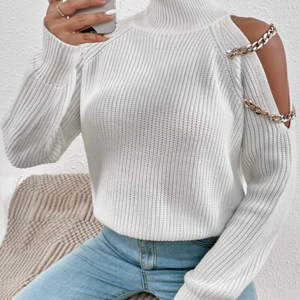 White turtleneck sweater with chain-accented cutout shoulders for a trendy look.